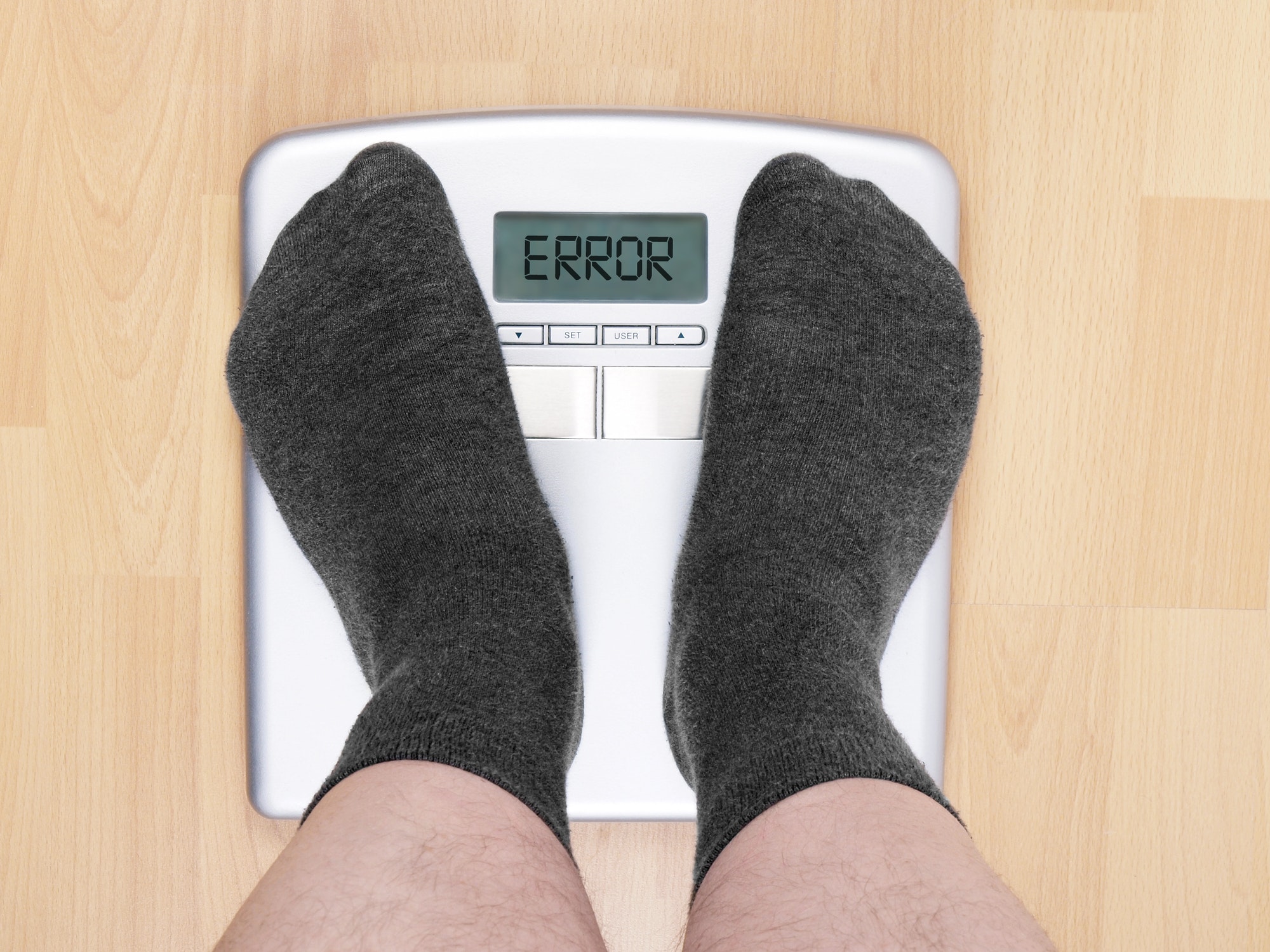 feet of overweight üerson standing on bathroom scales showing error